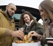 une famille mangeant des pizzas auprès de leur voiture